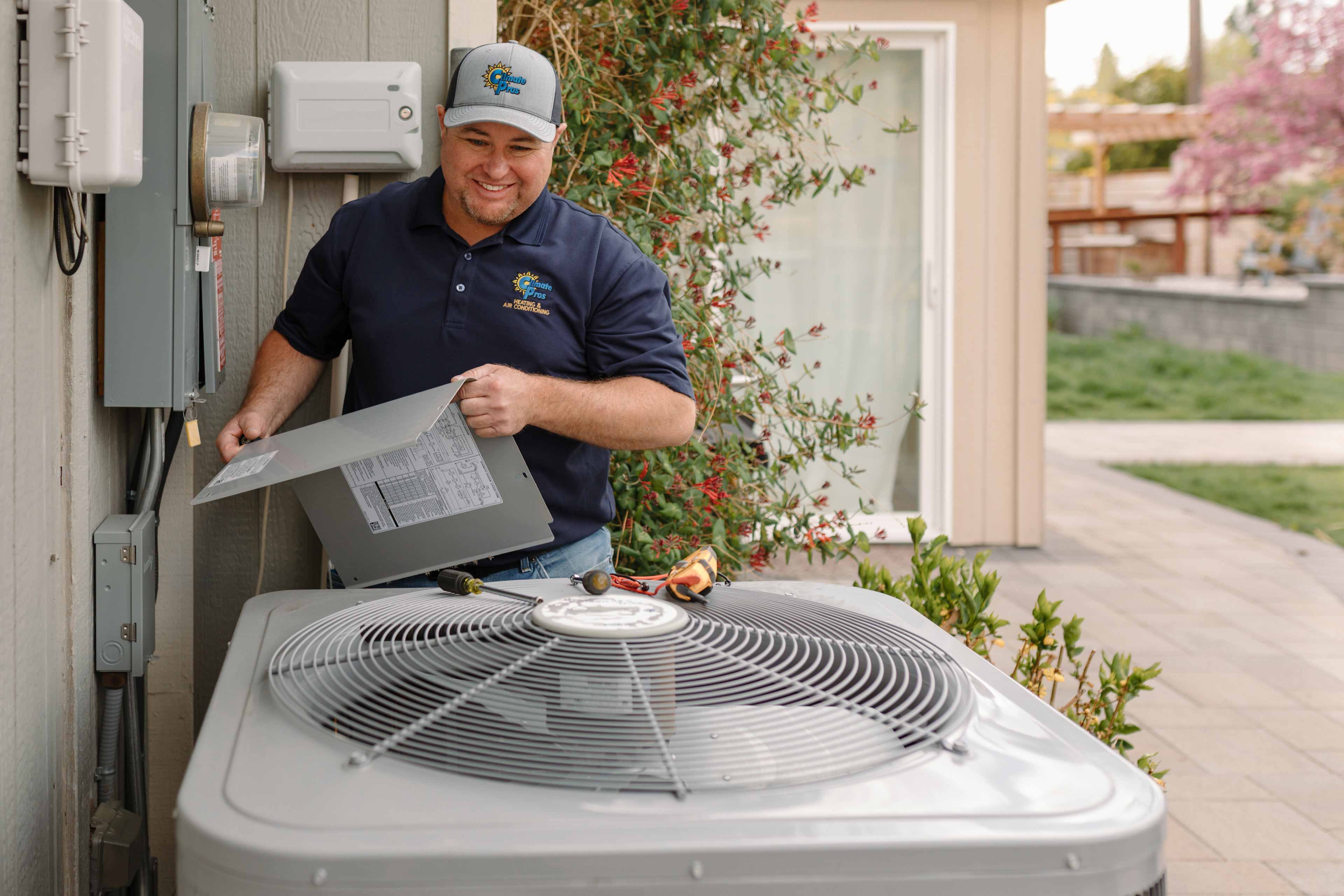 climate pros tech servicing the fan of a cooling unit