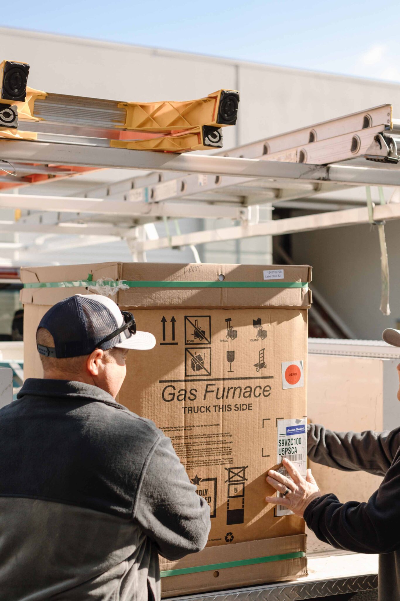 climate pros crew carrying a new gas furnace for a client